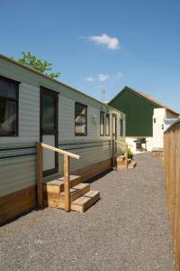 a mobile home with a porch and stairs next to it at tranquil holiday home Devon Cornwall border Bude in Pyworthy