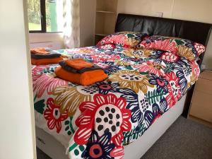 a bed with a colorful comforter on it at tranquil holiday home Devon Cornwall border Bude in Pyworthy