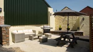 a patio with a picnic table and an umbrella at tranquil holiday home Devon Cornwall border Bude in Pyworthy