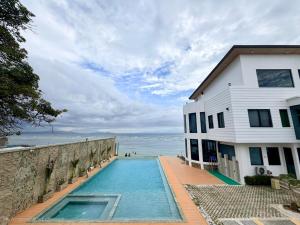 a house with a swimming pool next to the ocean at PlayaLolita Beach Resort in Calatagan
