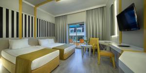 a hotel room with two beds and a desk and a television at Grand Ring Hotel in Beldibi