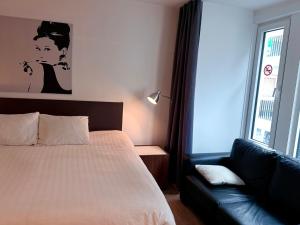 a bedroom with a bed and a couch next to a window at Logies Zen aan Zee in Ostend