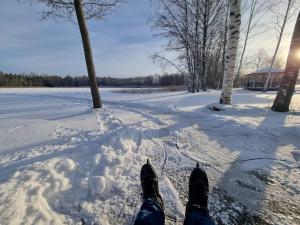 a person standing in the snow with their shoes on at Berzkrasti Lake House with Private Sauna & Beach in Sigulda