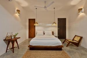 a bedroom with a bed and a chair and lights at La Cove in Matara