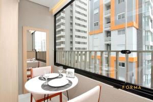 a balcony with a table and chairs and a large window at Raízes Studios Tatuapé – Mitre 4 in São Paulo