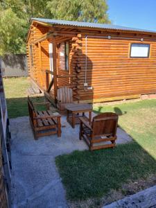 a cabin with two chairs and a picnic table and a bench at Cabaña Doña Loly in Olavarría