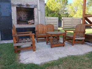 three wooden chairs and a table and a bench at Cabaña Doña Loly in Olavarría