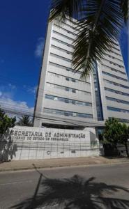 a tall building with a palm tree in front of it at Lofts portal 225 unid 01 in Recife
