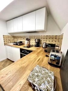 a kitchen with white cabinets and a wooden counter top at Canopée - Appartement - Hyper centre ville in Quimper