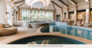 a pool in a hotel with chairs and a swimming pool at Mottram Hall in Macclesfield