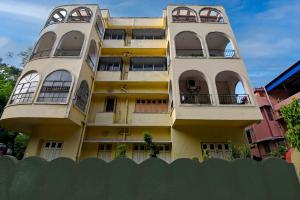 a tall yellow building with windows and a fence at Hotel Soft Petal BB Block in Kolkata +26 photos