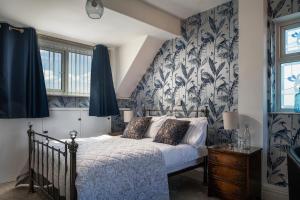 a bedroom with a bed with a blue and white patterned wall at Rosaire Guest House in Llandudno