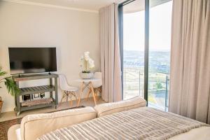 a living room with a couch and a large window at Ad Astra Studio Apartment - Waterfall in Midrand
