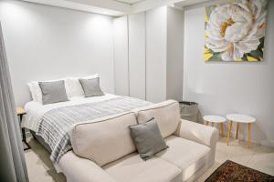 a white bedroom with a bed and a couch at Ad Astra Studio Apartment - Waterfall in Midrand +16 photos