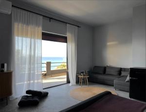 a living room with a couch and a view of the ocean at hellofrom Beach House in Loutrá Elevtherón