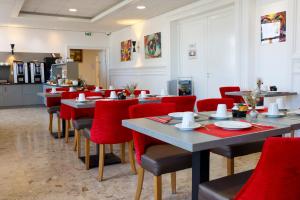 a dining room with tables and red chairs at Hotel Le Cercle in Cherbourg en Cotentin