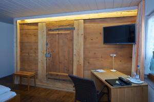 Zimmer mit einer Holzwand, einem Schreibtisch und einem TV in der Unterkunft Gasthof Bären in Ranflüh