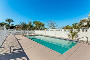 a swimming pool with a white fence and trees at Red Roof Inn Panama City Beach in Panama City Beach