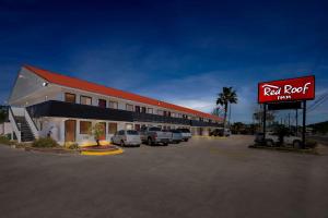a red roof inn with cars parked in a parking lot at Red Roof Inn Panama City Beach in Panama City Beach