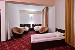 a hotel room with two beds and two chairs at Hotel Magic GT Trivale in Piteşti