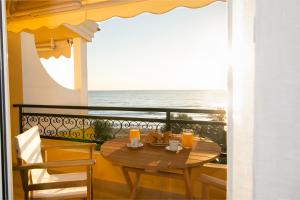 a table on a balcony with a view of the ocean at Glyfada Glow Suites by CorfuEscapes in Glyfada