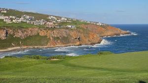 a golf course next to the ocean with houses on a cliff at Pinnacle Golf Estate Haven in Mossel Bay