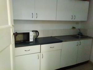 a kitchen with white cabinets and a microwave at JH Guest house in Durban