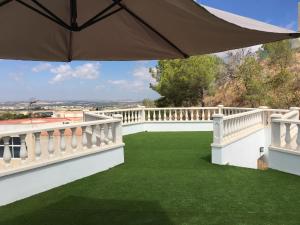 a balcony with green grass and an umbrella at Apartamento Los Pinos in San Miguel de Salinas