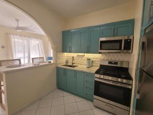 a kitchen with green cabinets and a stove and microwave at Sunny Bluu Villas in Meads Bay
