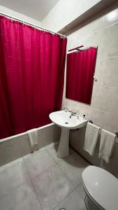 a bathroom with a sink and a red shower curtain at Hotel JSF in Horta