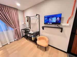 a room with a tv on a wall with a chair at AURELIA Stay in Brinchang