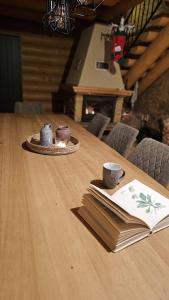 a table with a book and a cup and a plate of food at Zrubová chata Jakub in Oravská Lesná