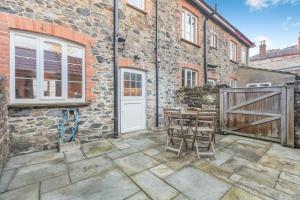 a patio with a table and chairs in front of a brick building at 2 Bed in Sticklepath oc-l33312 in Sticklepath