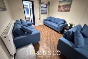 a living room with blue couches and a tv at Sandringham & Spa Villa in Thornton