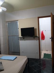 a room with a bed and a flat screen tv at Casa Hum com cozinha americana in Araruama