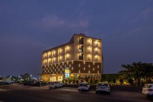 a large building with cars parked in a parking lot at Hotel Neptune Mansingh Inn in Morbi