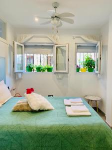 a bedroom with a green bed with three windows at Verde Oliva Albero Limon in Antequera