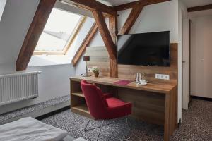 a room with a desk with a tv and a red chair at Gasthaus Alter Wirt in Oberneuching