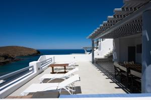a balcony with white chairs and a table and the ocean at The Eagle Merchia Mykonos in Merchia Beach