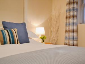 a bedroom with a bed with a blue pillow and a lamp at Dairy Cottage in Marros