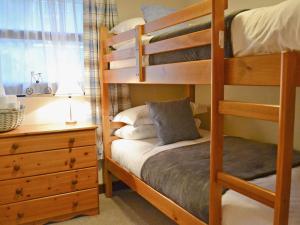 a bedroom with bunk beds with a dresser and a bed at Dairy Cottage in Marros +7 photos