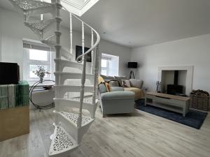 a living room with a spiral staircase in a house at Mid- Village Croft in Cairndow