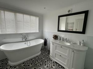 a bathroom with a tub and a sink and a mirror at Mid- Village Croft in Cairndow +23 photos