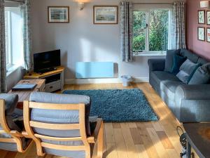 a living room with a couch and a tv at Whispering Pines - Uk51248 in Swyre