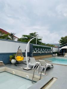 a patio with chairs and a swing next to a pool at 2020 Apartment Katampe in Mama