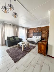 a bedroom with a bed and a couch and a table at Cozy Cottage in Langebaan