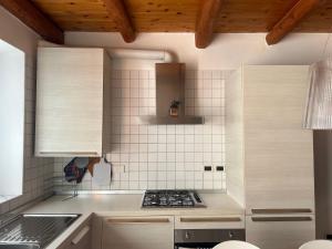 a kitchen with white tiled walls and wooden ceilings at Ancient village in Trieste