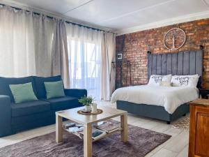 a living room with a bed and a blue couch at Cozy Cottage in Langebaan