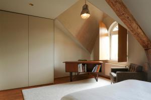 a bedroom with a bed and a desk and a window at GRAACE House Suites in Luxembourg