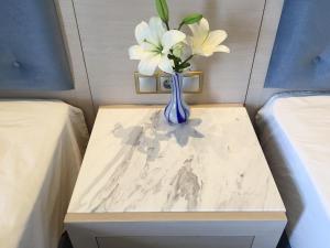 a blue vase with white flowers on a table between two beds at Vergos Hotel in Vourvourou